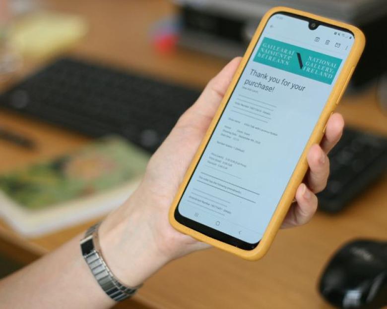 Hand holding a smartphone with a ticket confirmation email visible on screen