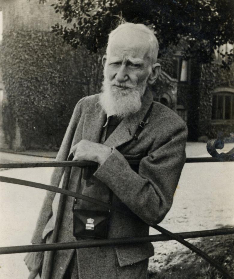 Photo of George Bernard Shaw leaning on a gate