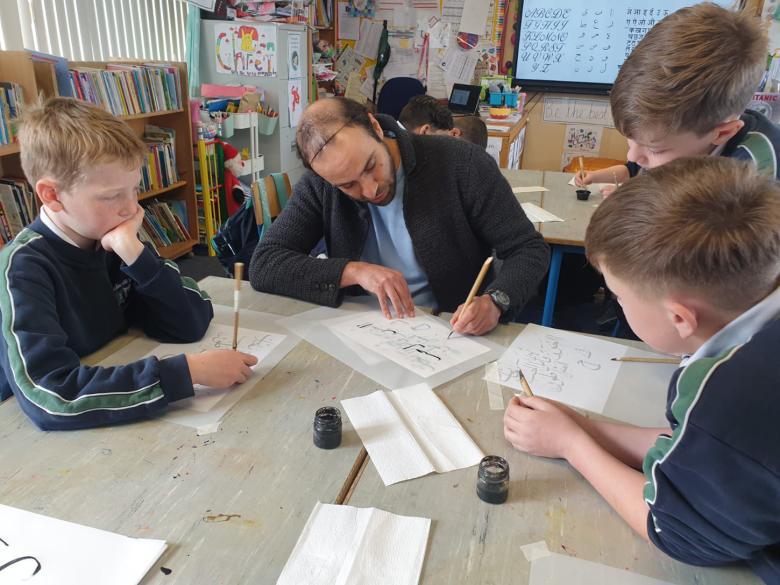 An artist drawing with three school students in a Your Gallery at School workshop