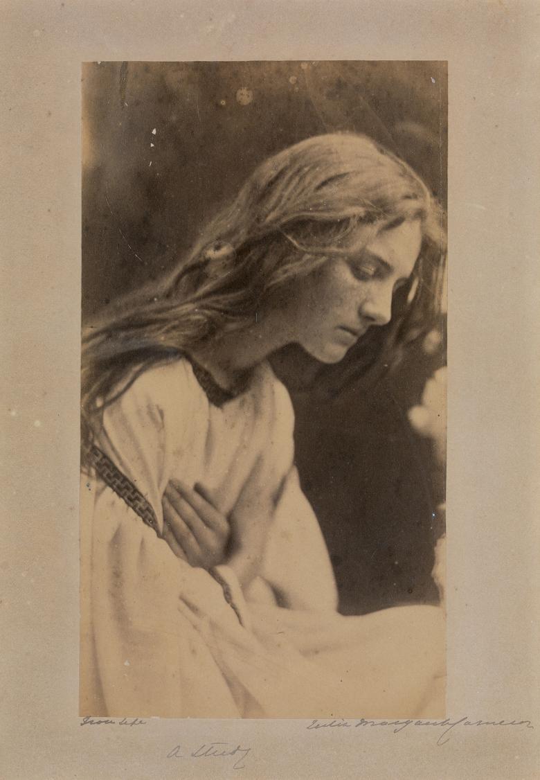 Black and white vintage photograph of a long-haired women with head bowed and hands crossed across chest