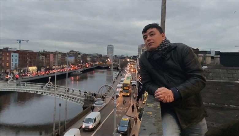A still from a documentary film. A stands on a rooftop - behind him, we can see the Liffey, with the Ha'Penny Bridge clearly visible.