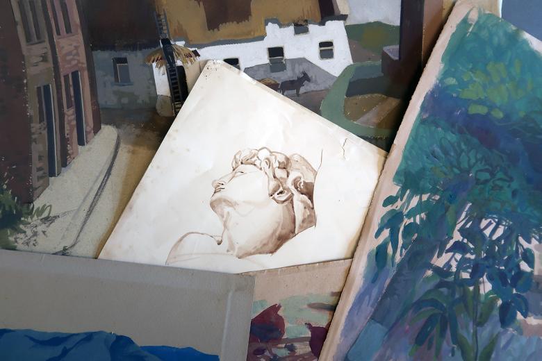 A variety of artworks in a pile, including sketches and oil paintings