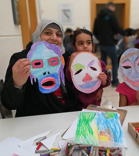 A family hold up the masks that they created at a drop-in family workshop at the National Gallery of Ireland.