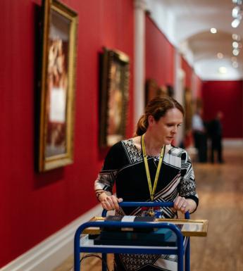 Woman pushing trolley of books through art gallery