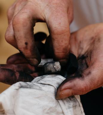 Hands holding charcoal and a cloth