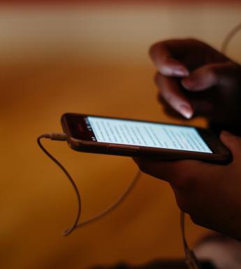 Someone holding a phone in their hands with headphones attached