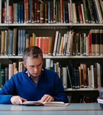 Man reading book at a table in a library