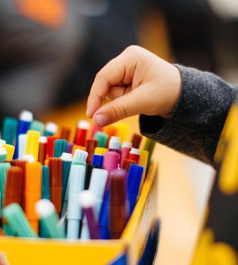 Photo of a child's hand reaching for a coloured marker in a box.