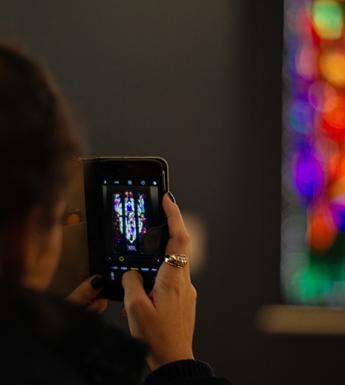 Photo of a woman using her phone to take a photo of stained glass in the National Gallery of Ireland.
