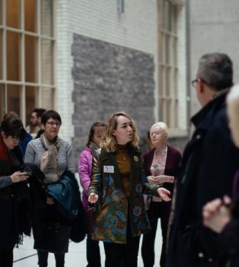 Photo of a tour guide speaking to a group of visitors in the courtyard of the National Gallery of Ireland.