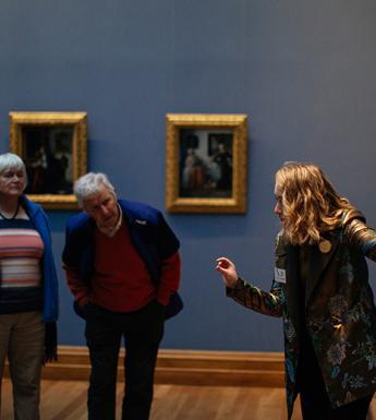 Tour guide speaking to a group of Gallery visitors in front of a painting
