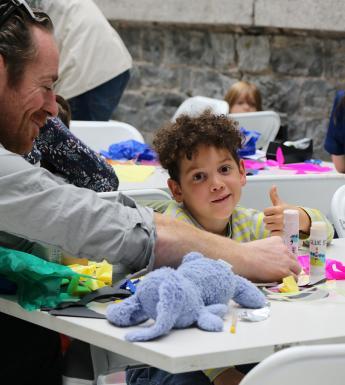 Photo of a boy and his father making art at a table.