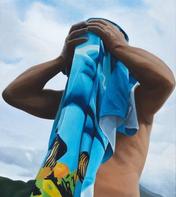 A figure holds a blue and yellow beach towel up to their face, apparently drying after a swim. Behind, we see blue cloudy skies, and green hills.