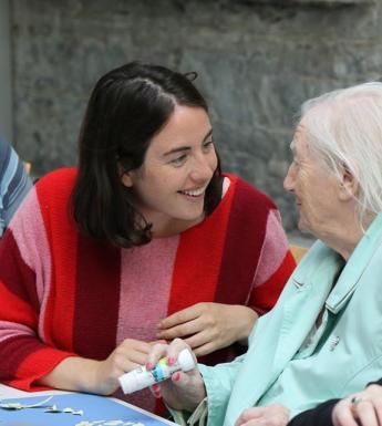 Photo of a young woman and older woman making crafts in an art workshop.