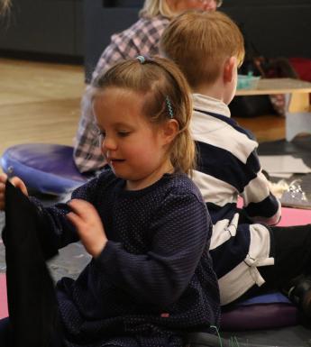 Photo of a child sitting on the floor taking part in an art workshop.