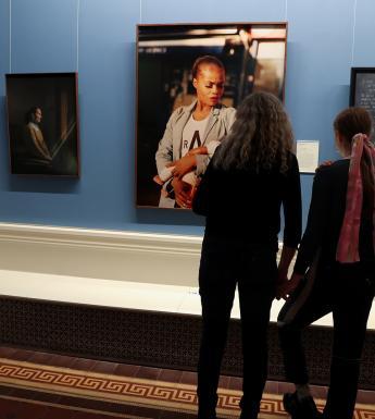 Photo of two women looking at three portraits in an exhibition