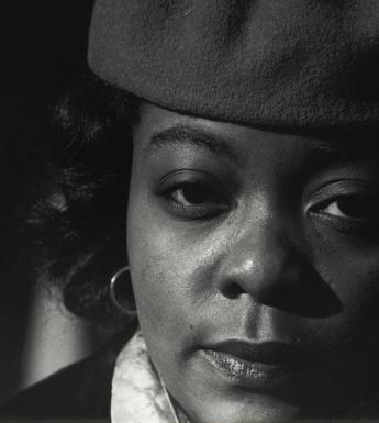 Black and white closely cropped photographic portrait of a woman wearing a hat