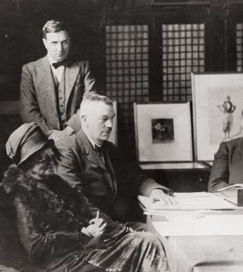 Vintage black and white photo of men and women seated at board table