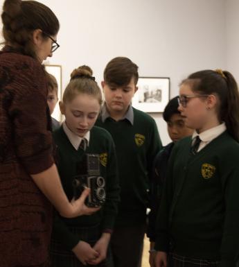 School kids looking at a vintage camera in an exhibition