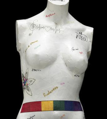 White mannequin bust with text graffiti and a rainbow coloured belt