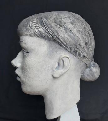 Black and white photograph of a clay sculpture of a female head
