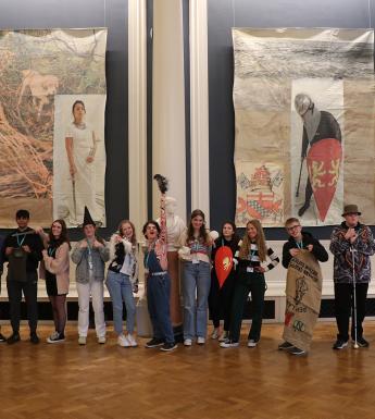 A group of TY work experience students in costume standing in front of Hughie O'Donoghue's art installation 'Original Sins'