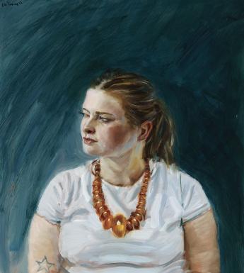 A woman sits against a dark blue background, her hands clasped in her lap and her head turned slightly to the left. She wears large amber beads around her neck, and a tattoo of a star is visible on her upper arm.