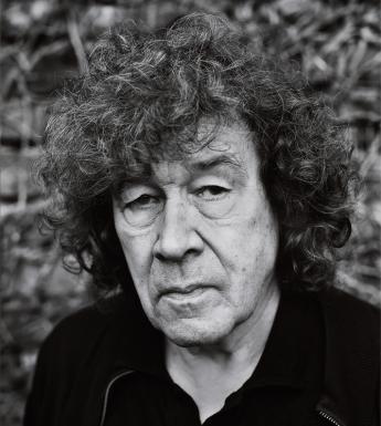 Black and white portrait of a man with dark curly hair and a black jacket.