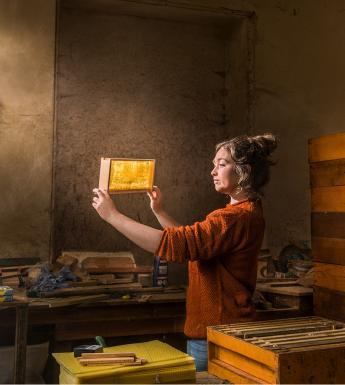 A woman holds a honeycomb up to the light.