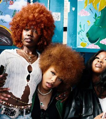 A photograph of four young black women. Two have ginger curly hair and are looking into the camera.