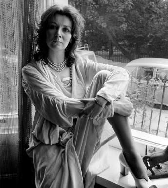 Black and white photograph of a woman sitting with her leg up on a windowsill.