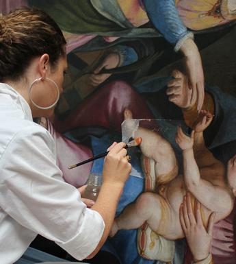 A conservator working on an oil painting