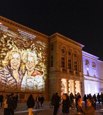 Merrion Square facade of the National Gallery of Ireland building with a portrait of two smiling people projected on to the facade 