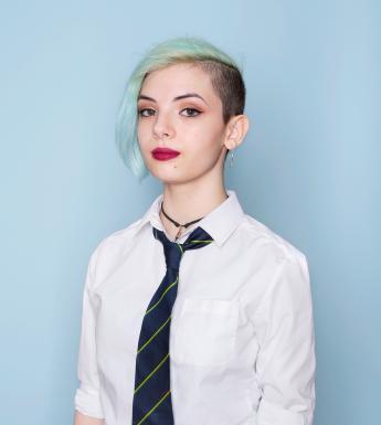 Colour photograph portrait by artist Mandy O'Neill showing teenage girl in school uniform against a pale blue background.