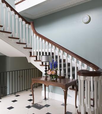 Grand staircase in a light blue room with black and white tiles