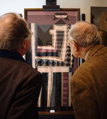 Photo of two men with their backs to the camera, looking at a painting on an easel.