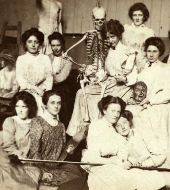 Vintage black and white photo of women posing with a medical skeleton model