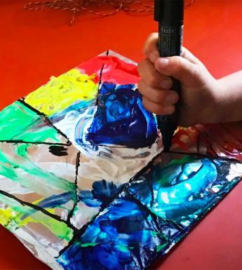 Young child making a stained glass inspired painting with colourful paint