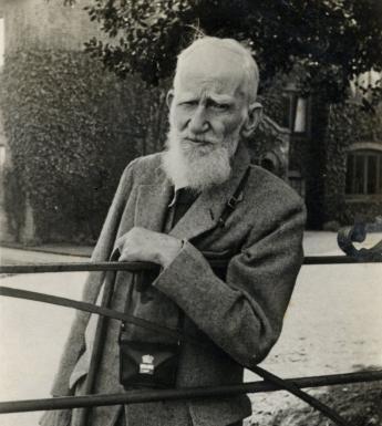 Photo of George Bernard Shaw leaning on a gate