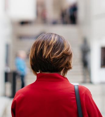 Photo of a woman with her back to the camera, wearing a red coat, standing in the lobby of the Millennium Wing of the National Gallery of Ireland.