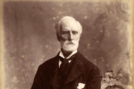 A black and white photograph in three quarter length of a man in a suit.