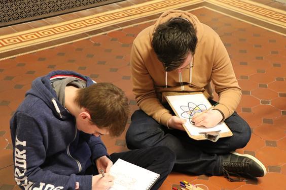 Photo of two teenage boys sitting on the floor drawing