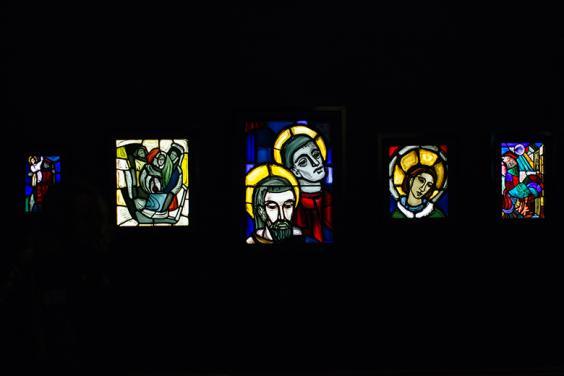 Photo of illuminated stained glass work by Evie Hone on display in a darkened room in the National Gallery of Ireland.