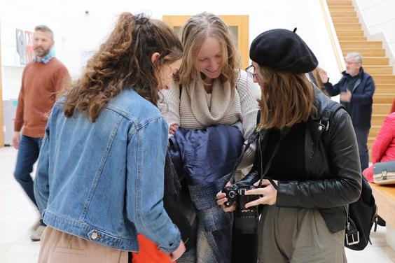 Photo of three young women looking at a digital camera screen