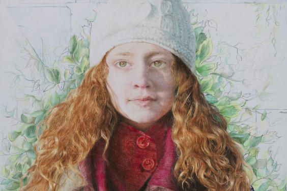 A young woman facing us, with her hands (in woolen mittens) clasped in front of her. She is wrapped in a number of different scarves, and wears a white wool hat. Her long auburn hair falls over her shoulders, and behind her there is green foliage.  