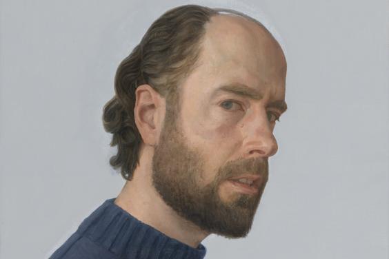 The subject of the portrait is standing side-on to the viewer, but his head is turned to look directly at us. He wears a navy woollen jumper.
