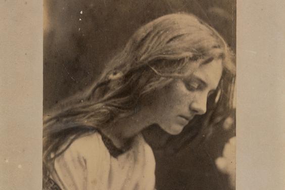 Black and white vintage photograph of a long-haired women with head bowed and hands crossed across chest