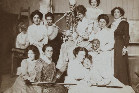 Vintage black and white photo of women posing with a medical skeleton model