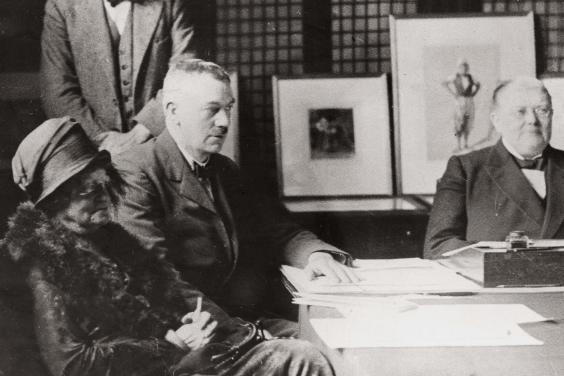 Vintage black and white photo of men and women seated at board table
