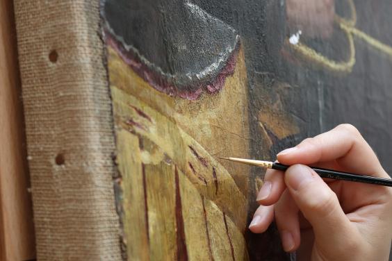 A detail of a conservator's hand with a brush, working on adjusting old discoloured retouchings on Lavinia Fontana's The Visit of the Queen of Sheba to King Solomon